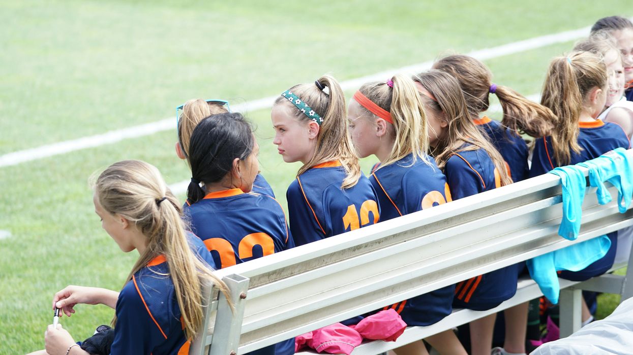 middle school girls sit on a bench during a sports game