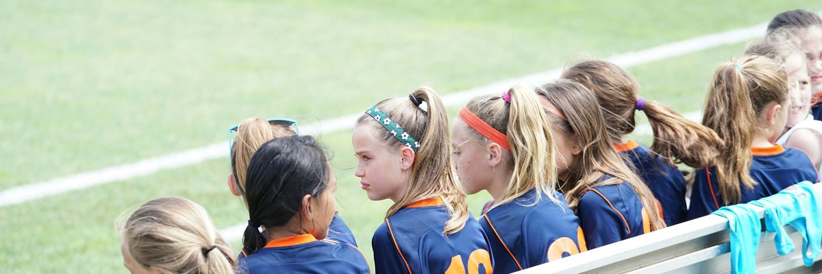 middle school girls sit on a bench during a sports game